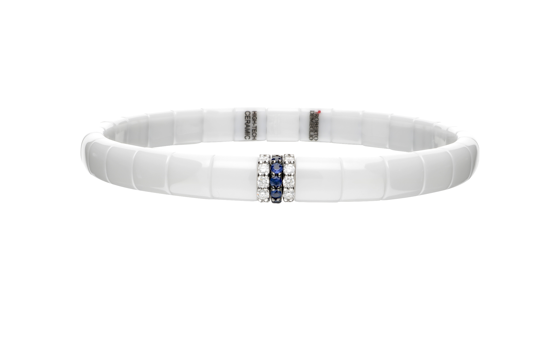A white ceramic bangle bracelet with a textured, segmented exterior and a central silver-toned clasp adorned with blue sapphires and clear crystals, shown on a plain white background.